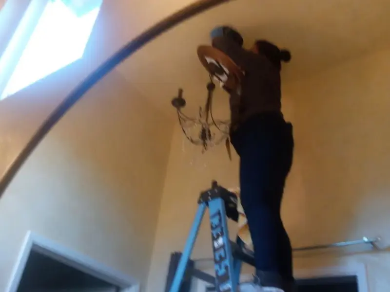 Electrician installing a chandelier in a York residence